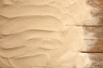 Photo of Beach sand on wooden background, top view with space for text