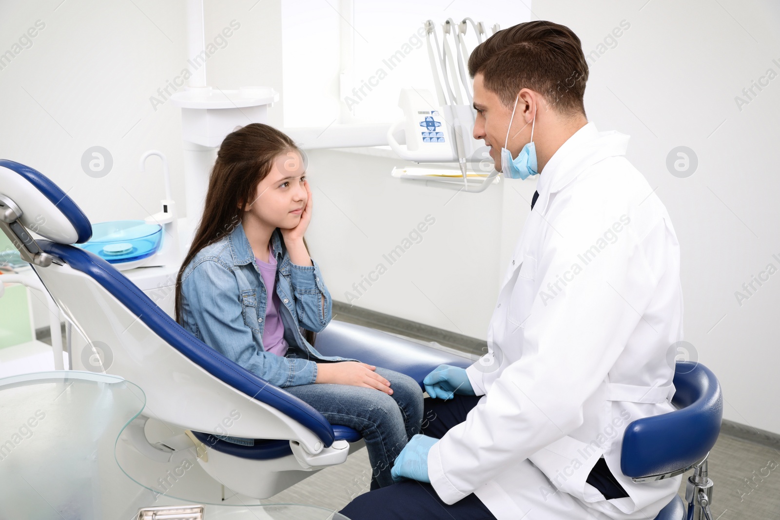 Photo of Professional dentist working with little girl in clinic