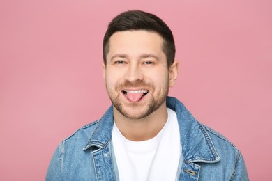 Happy man showing his tongue on pink background