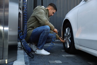 Handsome man inflating tire at car service