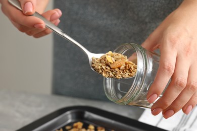 Photo of Woman putting granola into glass jar, closeup