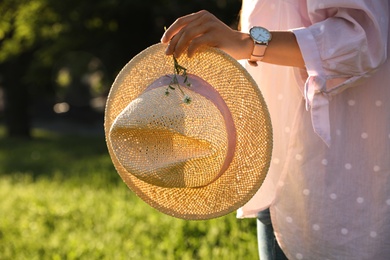 Young woman with straw hat and flowers outdoors on sunny day, closeup