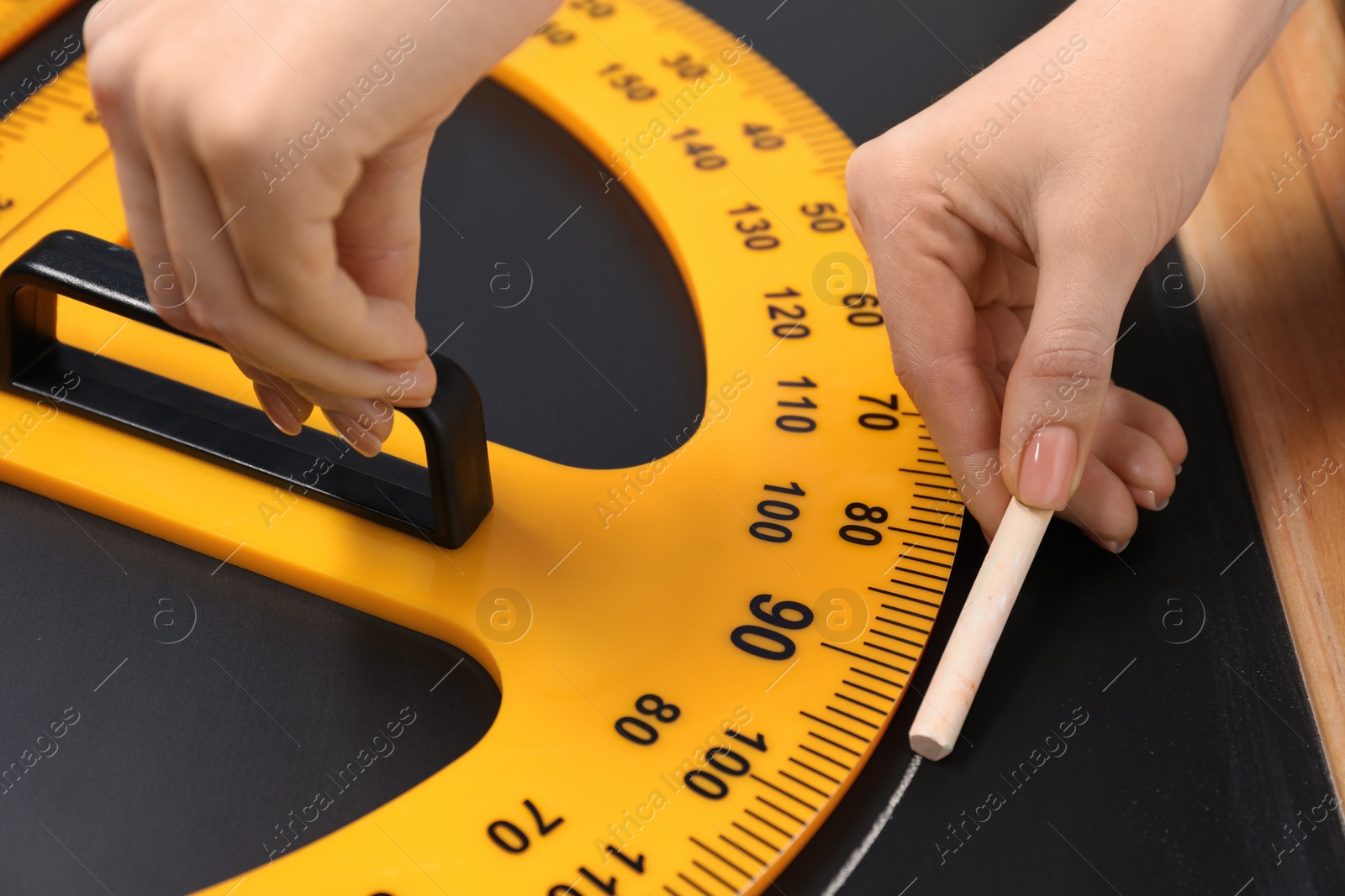 Photo of Woman drawing with chalk and protractor on blackboard, closeup