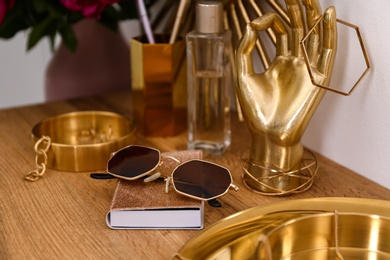 Photo of Composition with gold accessories on dressing table near white wall