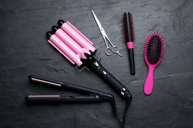 Flat lay composition of professional hairdresser tools on dark grey table