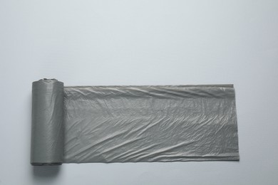 Roll of grey garbage bags on light background, top view