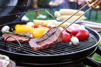 Photo of Barbecue grill with meat and vegetables outdoors, closeup