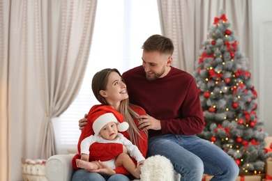 Photo of Happy family with cute baby in room decorated for Christmas holiday