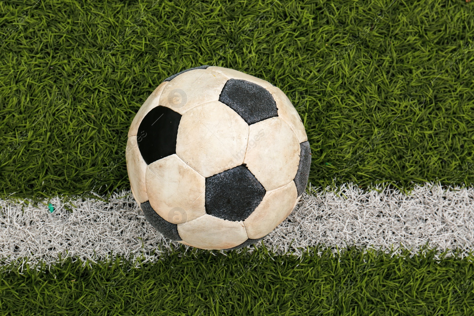 Photo of Dirty soccer ball on green football field, top view