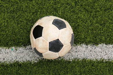 Photo of Dirty soccer ball on green football field, top view