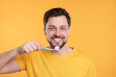 Happy man holding plastic toothbrush on yellow background. Mouth hygiene