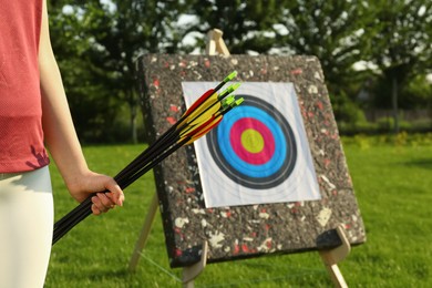Photo of Woman with arrows near archery target in park, closeup