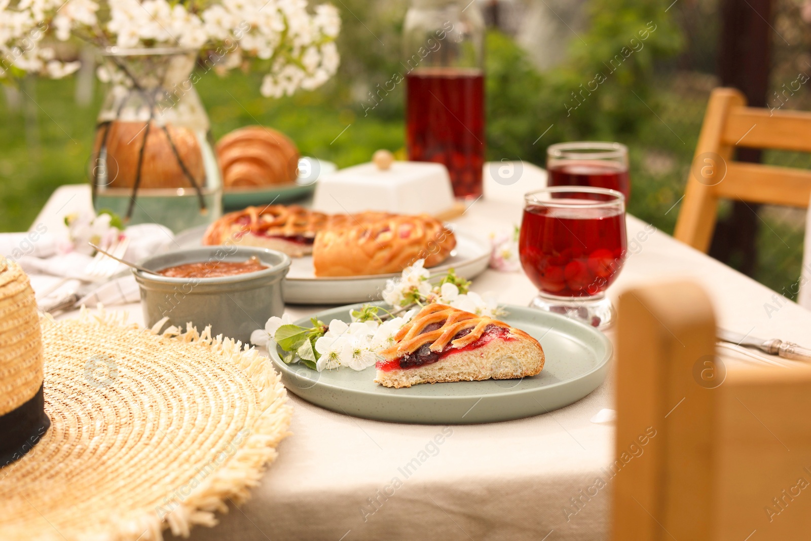 Photo of Stylish table setting with beautiful spring flowers, fruit drink and pie in garden