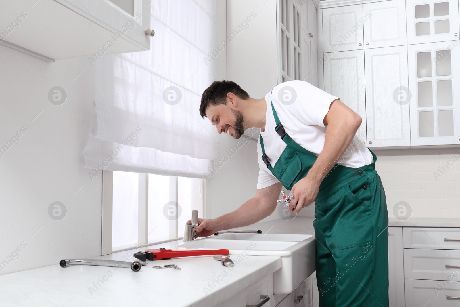 Photo of Professional plumber fixing water tap in kitchen