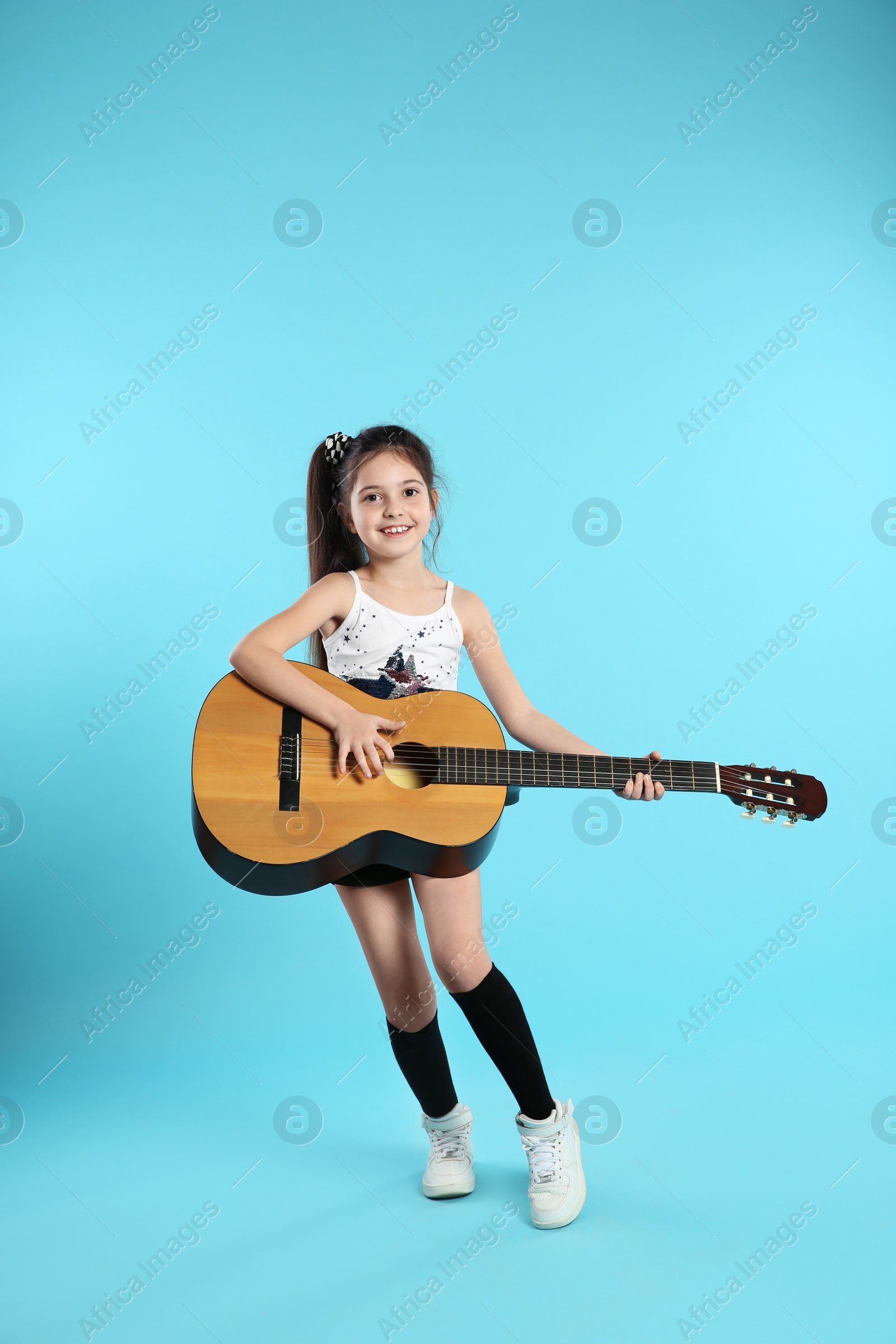 Photo of Cute little girl playing guitar on color background