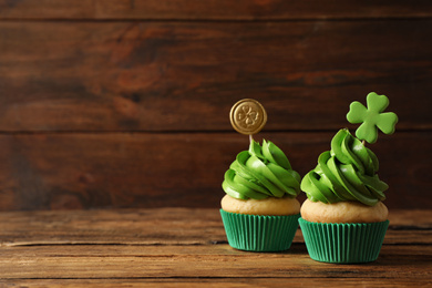 Delicious decorated cupcakes on wooden table, space for text. St. Patrick's Day celebration