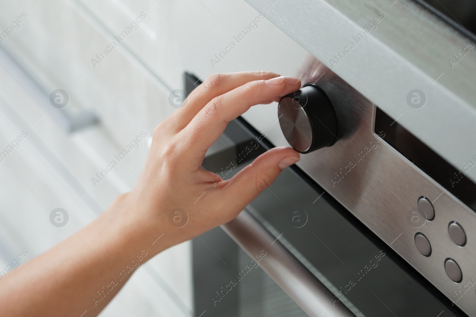 Photo of Woman regulating cooking mode on oven panel, closeup