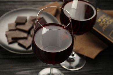 Tasty red wine and chocolate on black wooden table, closeup