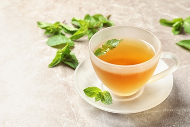 Photo of Cup with hot aromatic mint tea on table