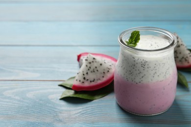 Photo of Delicious pitahaya smoothie, fruit and fresh mint on light blue wooden table, space for text