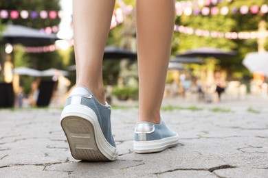 Photo of Woman in stylish shoes walking on city street, closeup