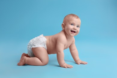Photo of Cute baby in dry soft diaper crawling on light blue background