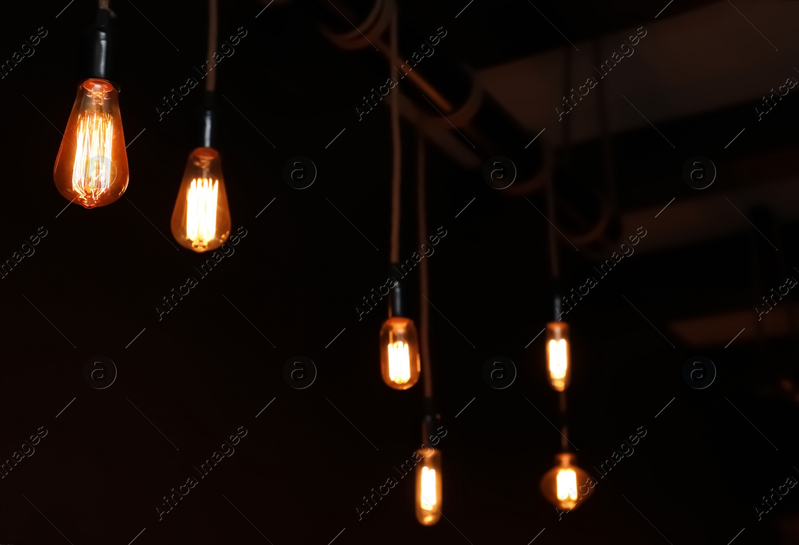 Photo of Glowing lamp bulbs in dark room. Interior element