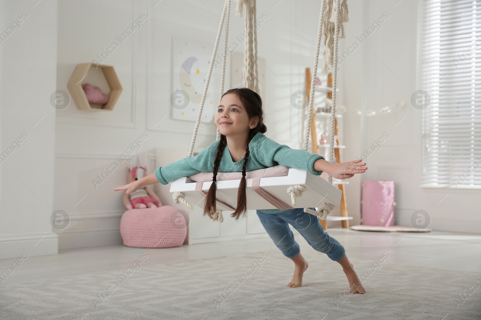 Photo of Cute little girl playing on swing at home