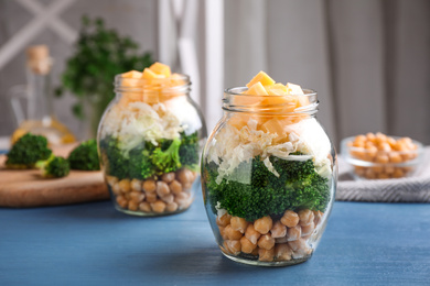 Photo of Healthy salad in glass jars on blue wooden table