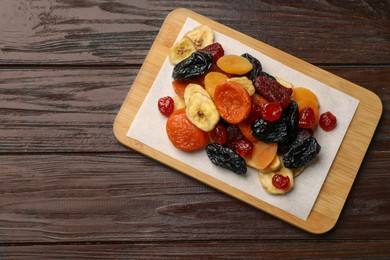 Photo of Mix of delicious dried fruits on wooden table, top view. Space for text