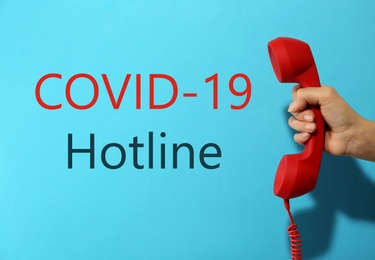 Image of Covid-19 Hotline. Woman with red handset and text on blue background, closeup