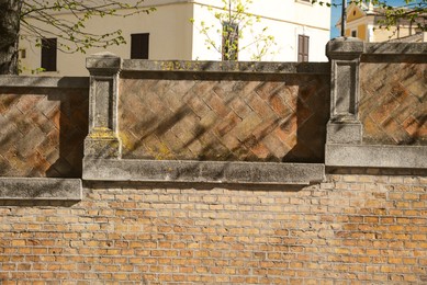 Photo of Old stone fence near building outdoors on sunny day