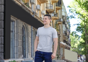 Photo of Young man in grey t-shirt outdoors. Mockup for design