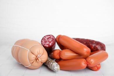 Photo of Different types of sausages on white tiled table