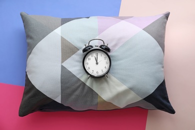 Photo of Decorative pillow and alarm clock on color background, top view