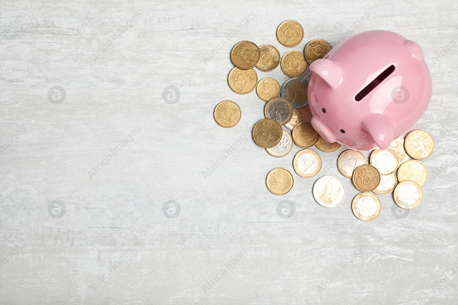 Photo of Piggy bank with coins on light background, top view. Space for text