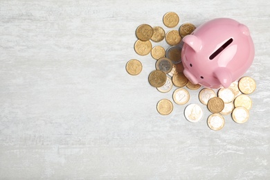Piggy bank with coins on light background, top view. Space for text