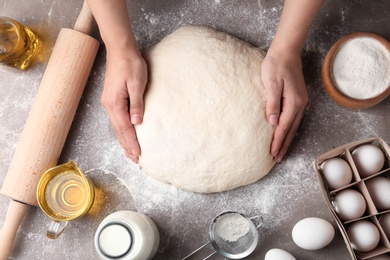 Photo of Female baker preparing bread dough at kitchen table, top view