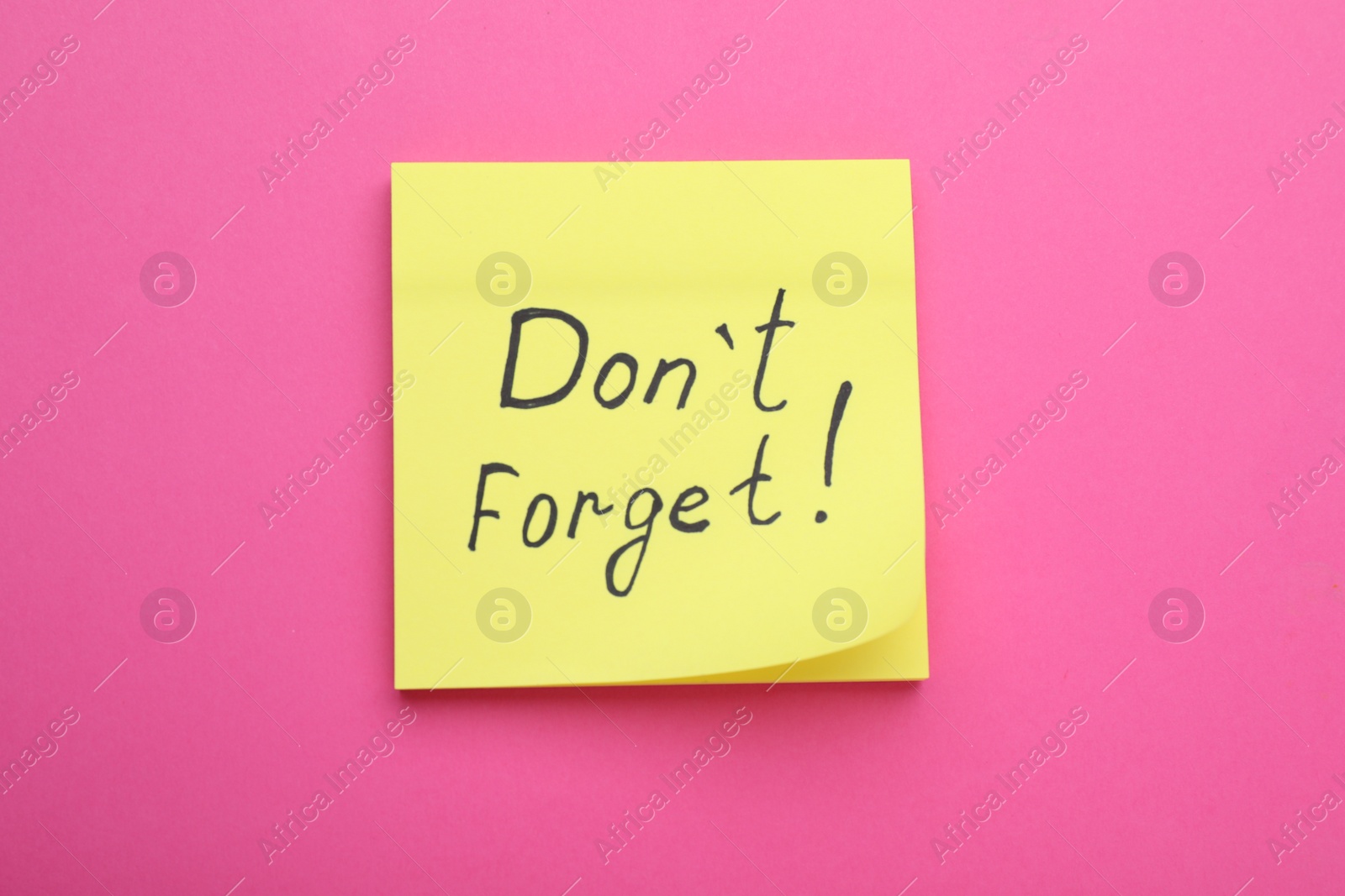 Photo of Paper note with phrase Don't Forget on pink background, top view