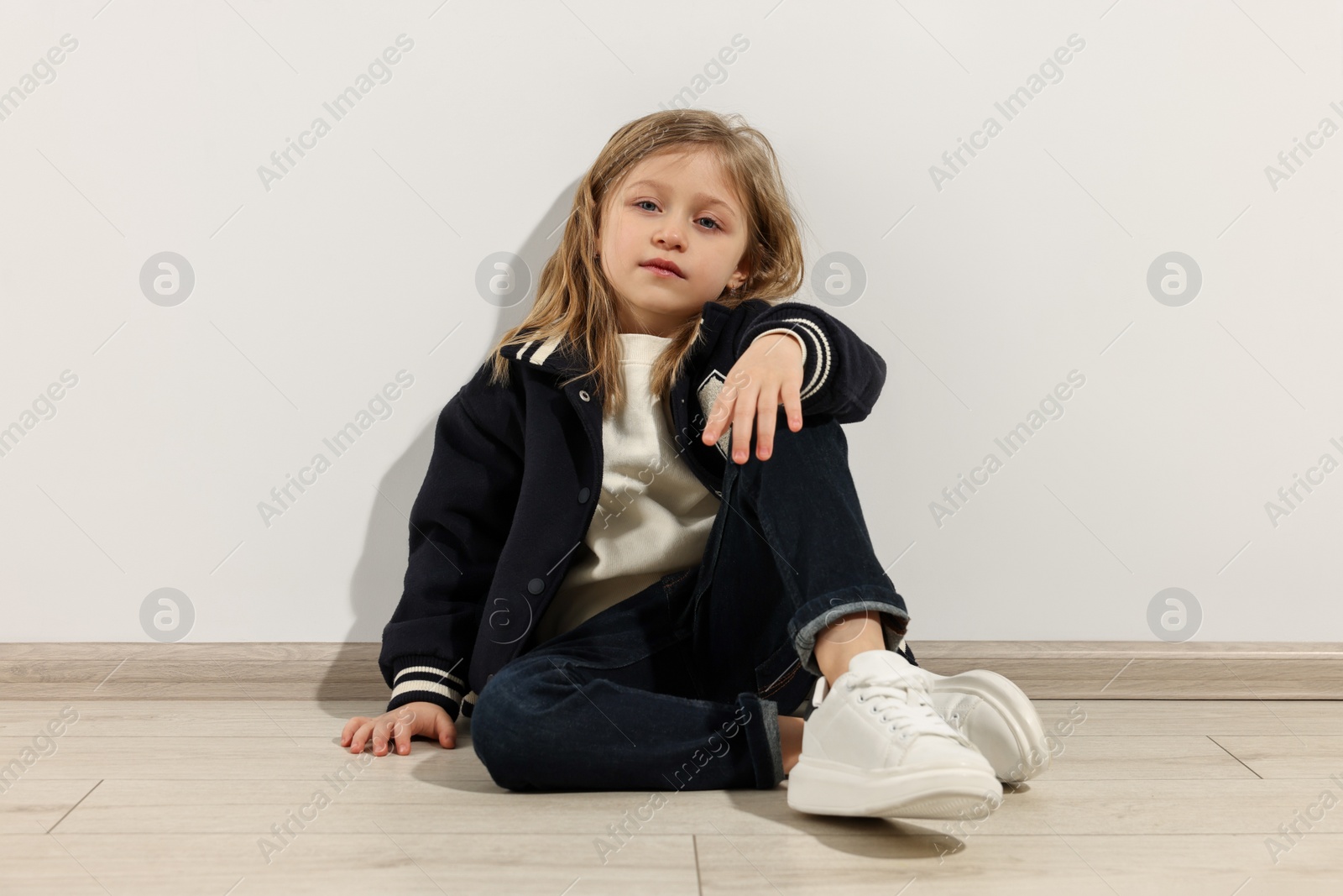 Photo of Fashion concept. Stylish girl sitting near white wall