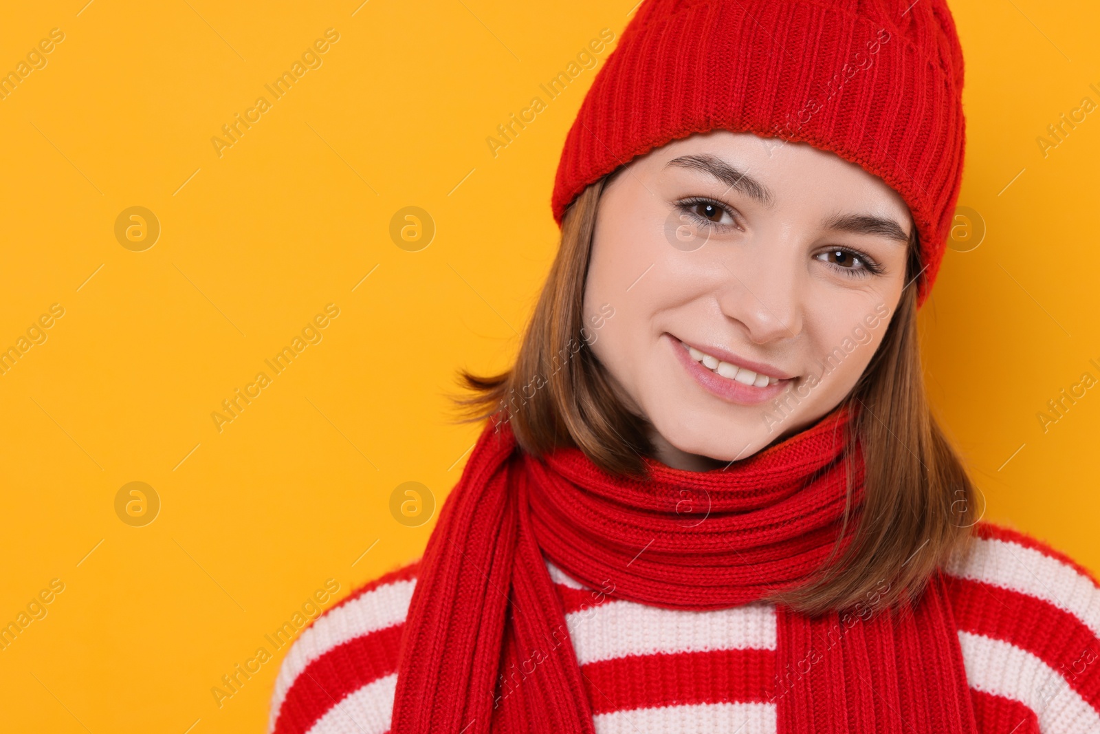 Photo of Beautiful woman in warm scarf on yellow background, space for text