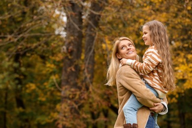 Photo of Happy mother with her daughter in autumn park. Space for text