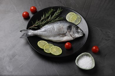 Photo of Fresh dorado fish, lime, tomatoes and rosemary on grey table, above view