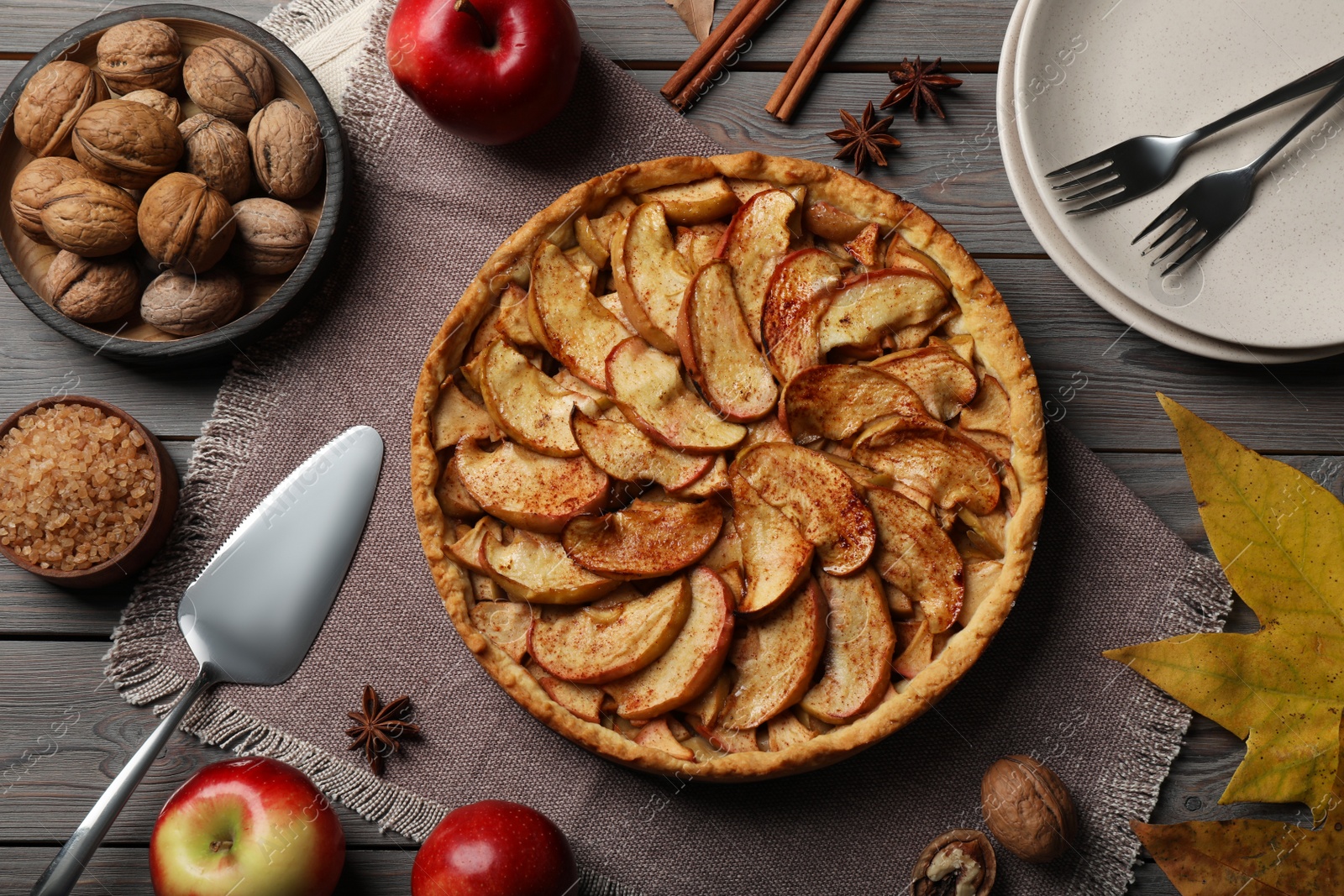 Photo of Delicious apple pie and ingredients on grey wooden table, flat lay