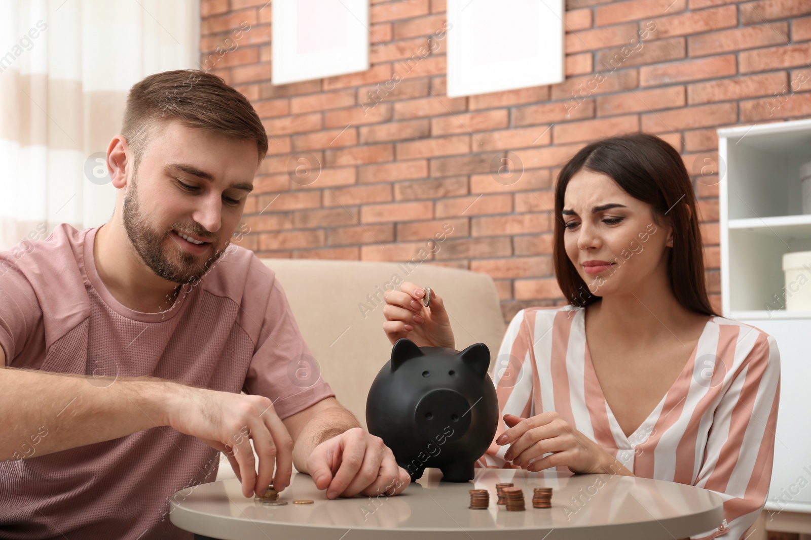 Photo of Unhappy young couple with money at home. Financial problems