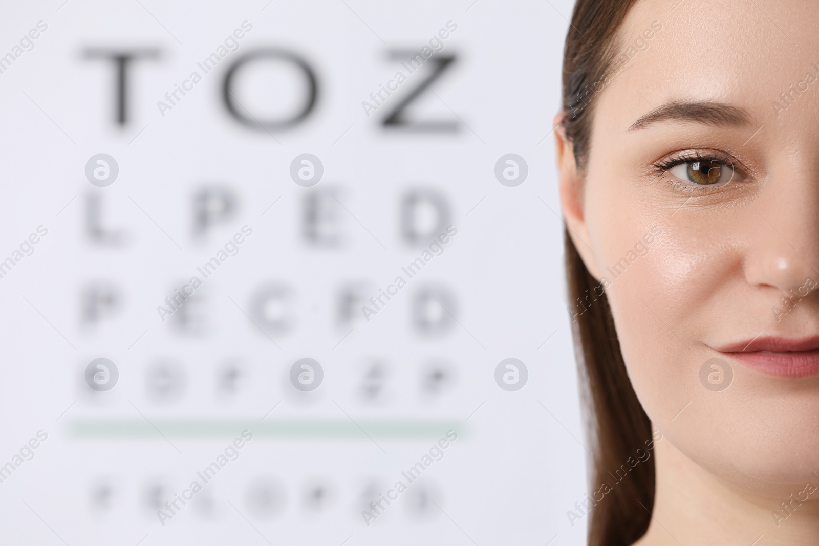 Photo of Young woman against vision test chart, closeup
