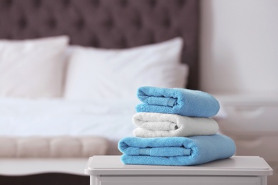Photo of Stack of clean towels on table in bedroom