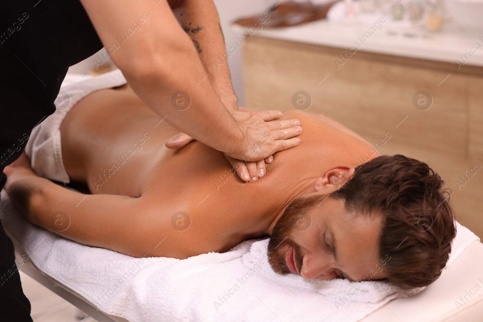 Photo of Man receiving professional back massage on couch in spa salon