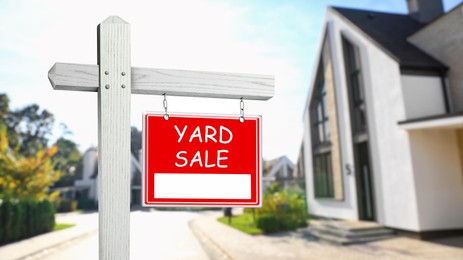Image of Sign with text YARD SALE and blurred view of modern house