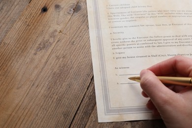 Photo of Woman signing Last Will and Testament at wooden table, closeup. Space for text